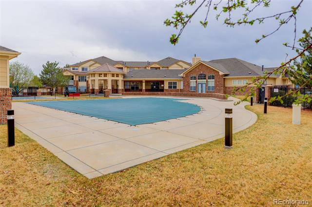Outdoor pool and concrete deck in front of a residential complex.