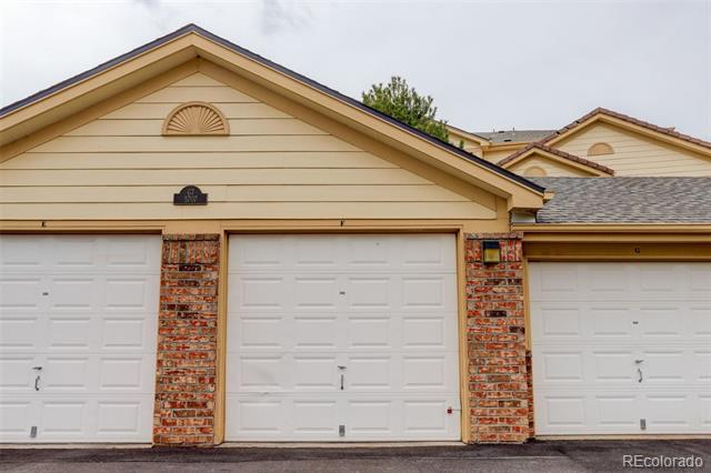 Attached garages with white paneled doors, brick columns, and tan gabled facades.