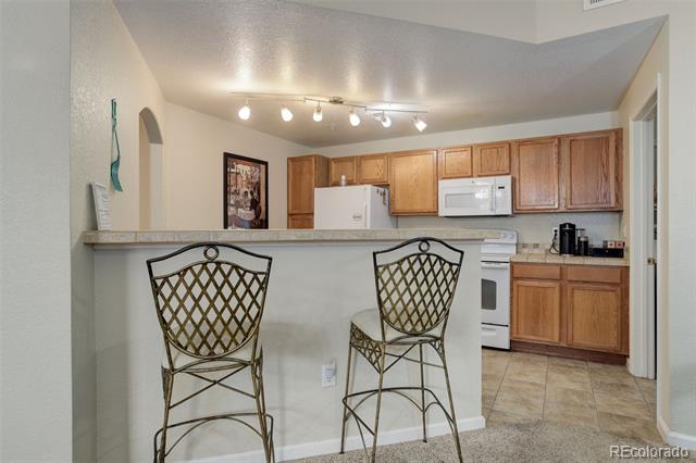 Kitchen with a raised breakfast bar, two metal stools, and honey-colored wood cabinets.