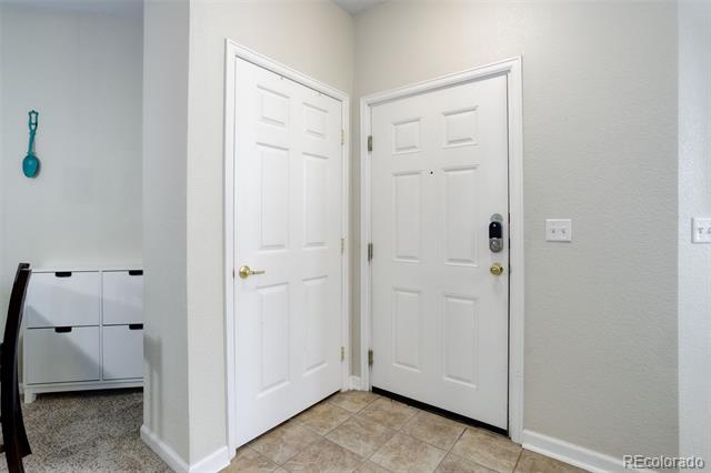 Entryway with two white paneled doors, a keypad lock, and tan tile flooring.