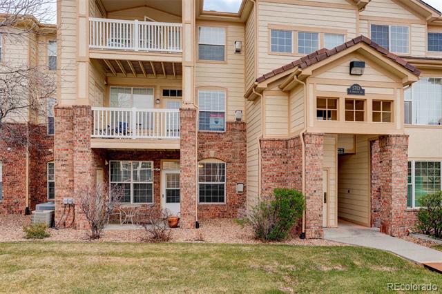 Residential building with brick lower walls, white-railed balconies, and a covered entrance.