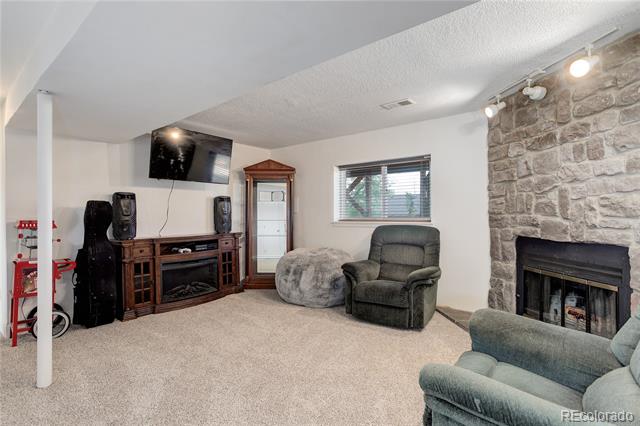 Basement living room with a stone fireplace, wall-mounted TV, and recliners.