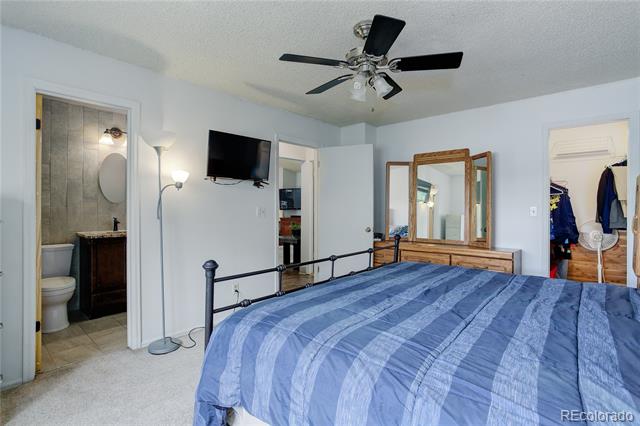 Bedroom with a blue striped bedspread, black metal bed frame, and an open doorway to an attached bathroom.