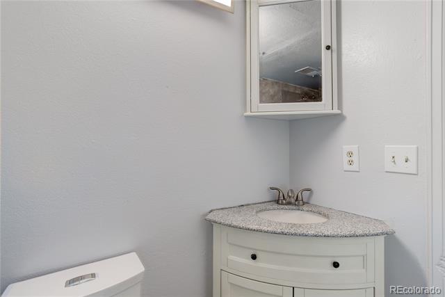 Bathroom vanity with a speckled gray countertop, chrome faucet, and wall mirror.