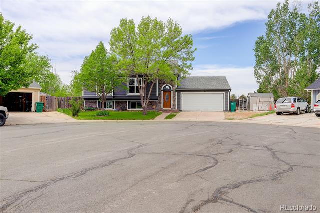 Two-story house with an arched front entry, white garage door, and mature trees.