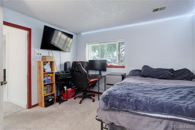 Bedroom with a large bed, computer desk, wall-mounted television, and window overlooking trees.