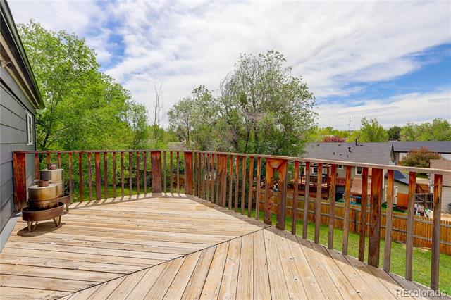 Wooden deck overlooking neighboring homes and leafy trees, with reddish-brown railings.
