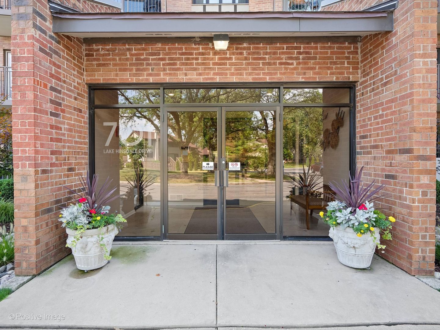 Brick building entrance with glass doors and flower planters at 7 Lake Hinsdale Drive.