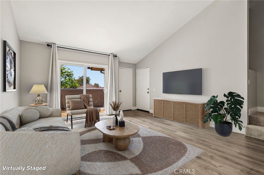 Virtually staged living room with a sofa, round coffee table, wall-mounted TV, and sliding glass doors.