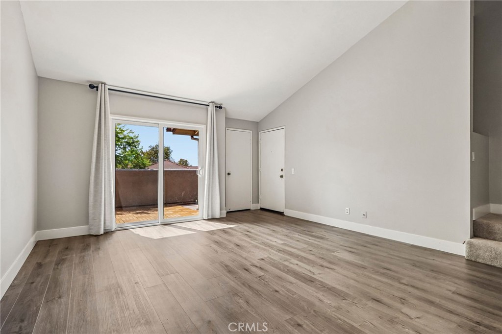Vacant living room with wood-look flooring and sliding glass doors opening to a patio.