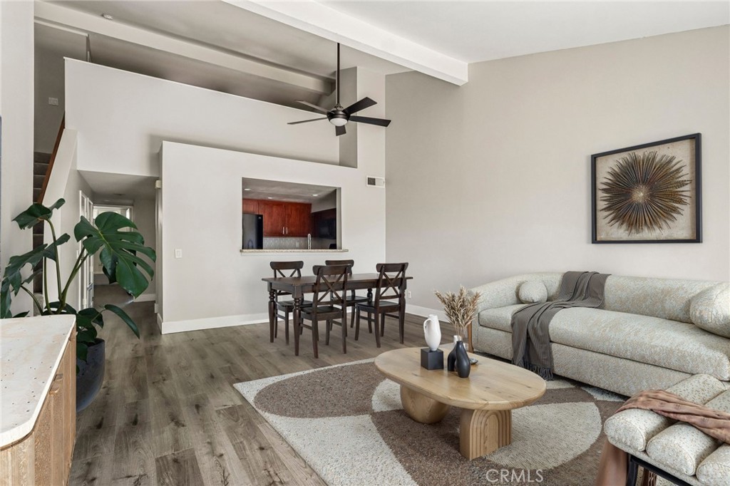 Open-plan living and dining room with a light sectional, oval coffee table, and vaulted ceiling.