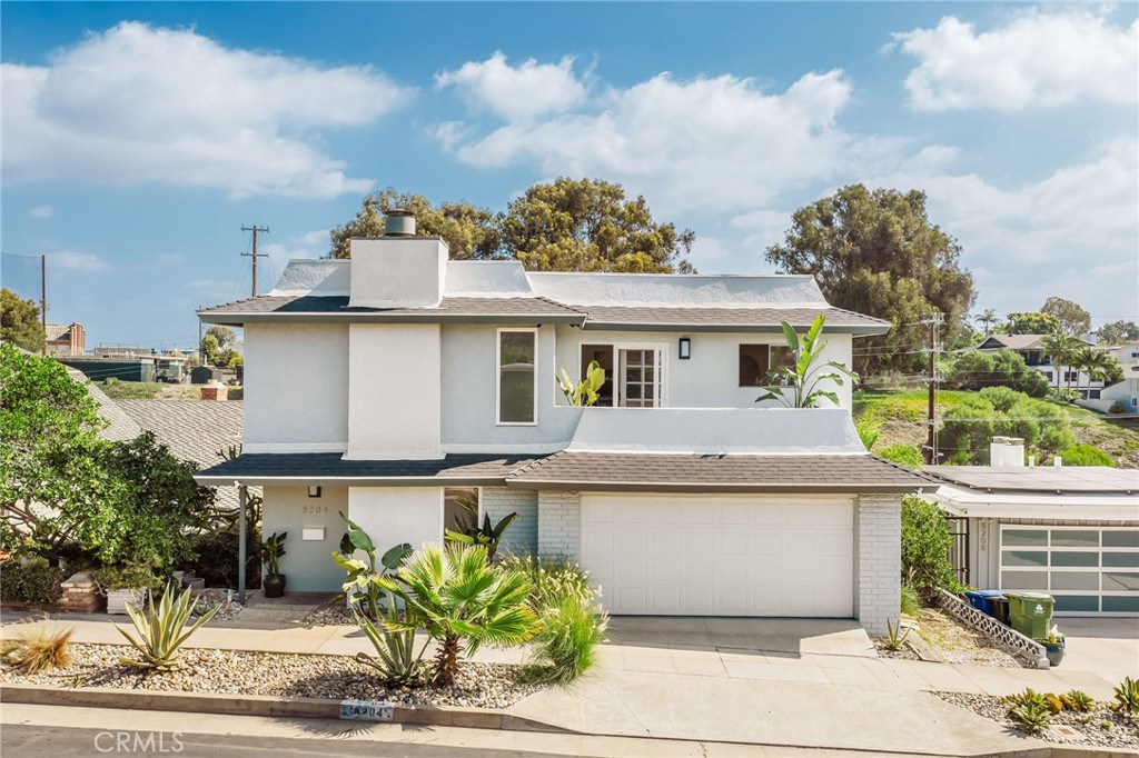 Two-story white stucco home with an attached garage and drought-tolerant front landscaping.