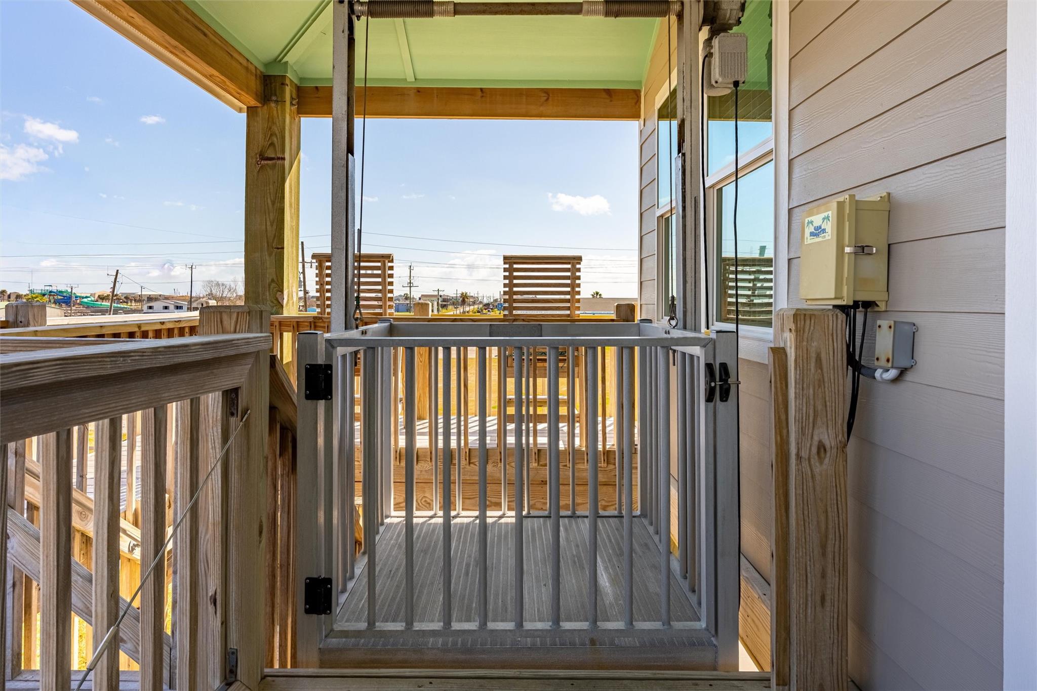 Raised wooden deck with a gated platform lift beside the home.