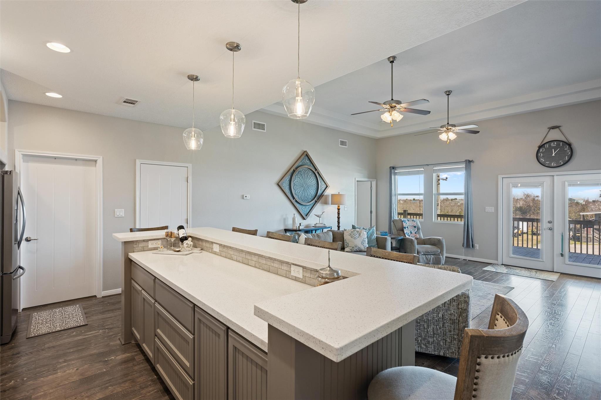 Open-plan kitchen and living area with a large island and glass doors to a deck.