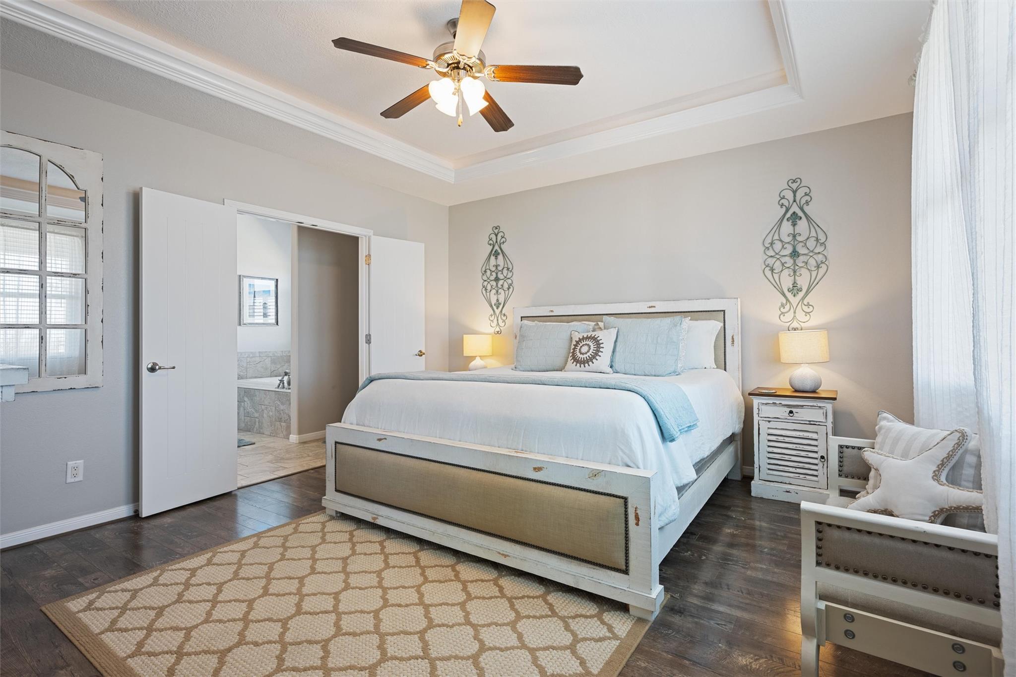 Bedroom with a white bed and pale blue bedding, opening to an adjoining bathroom.