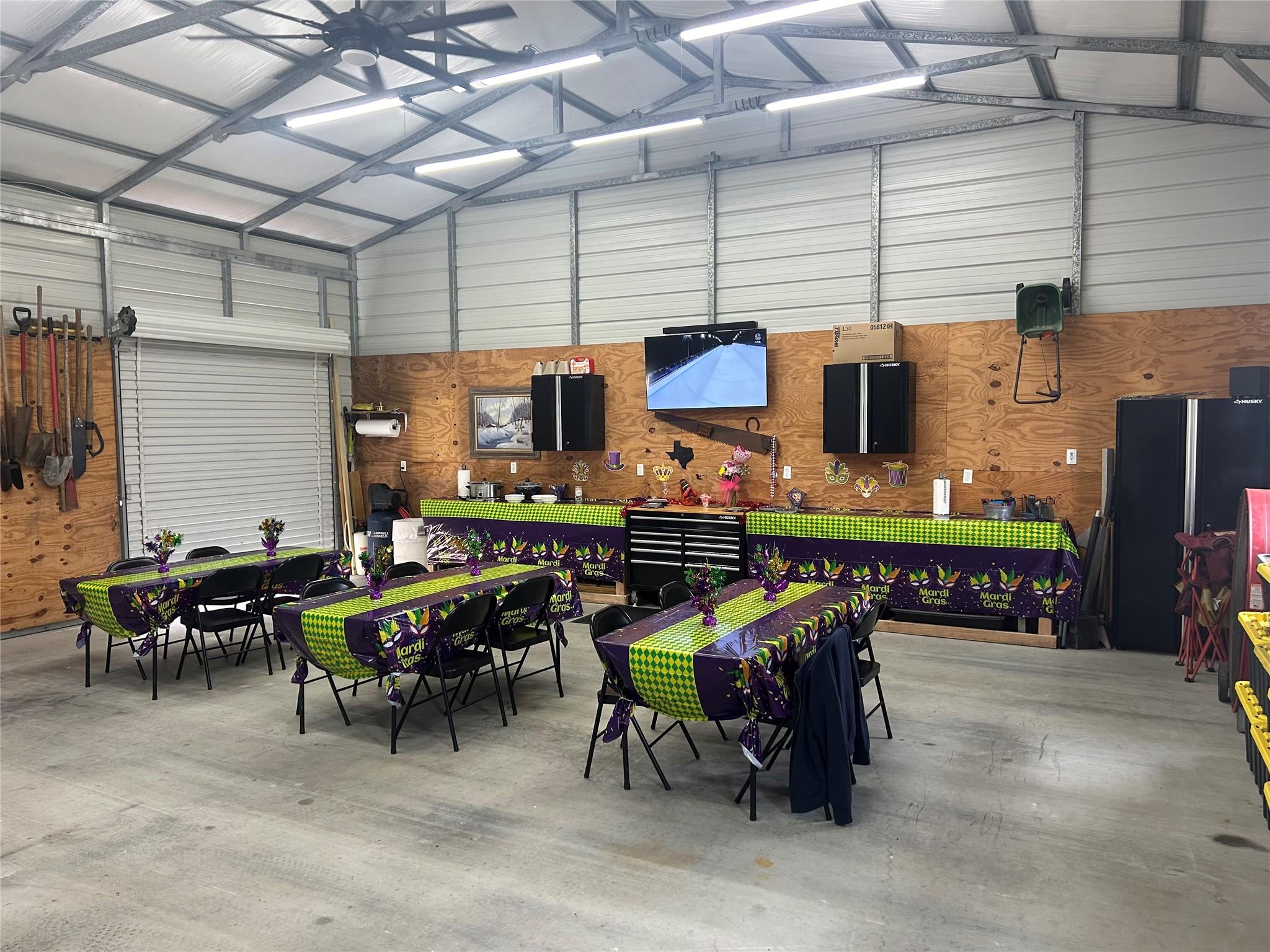 Garage workshop arranged for Mardi Gras with decorated tables, folding chairs, and wall-mounted storage.