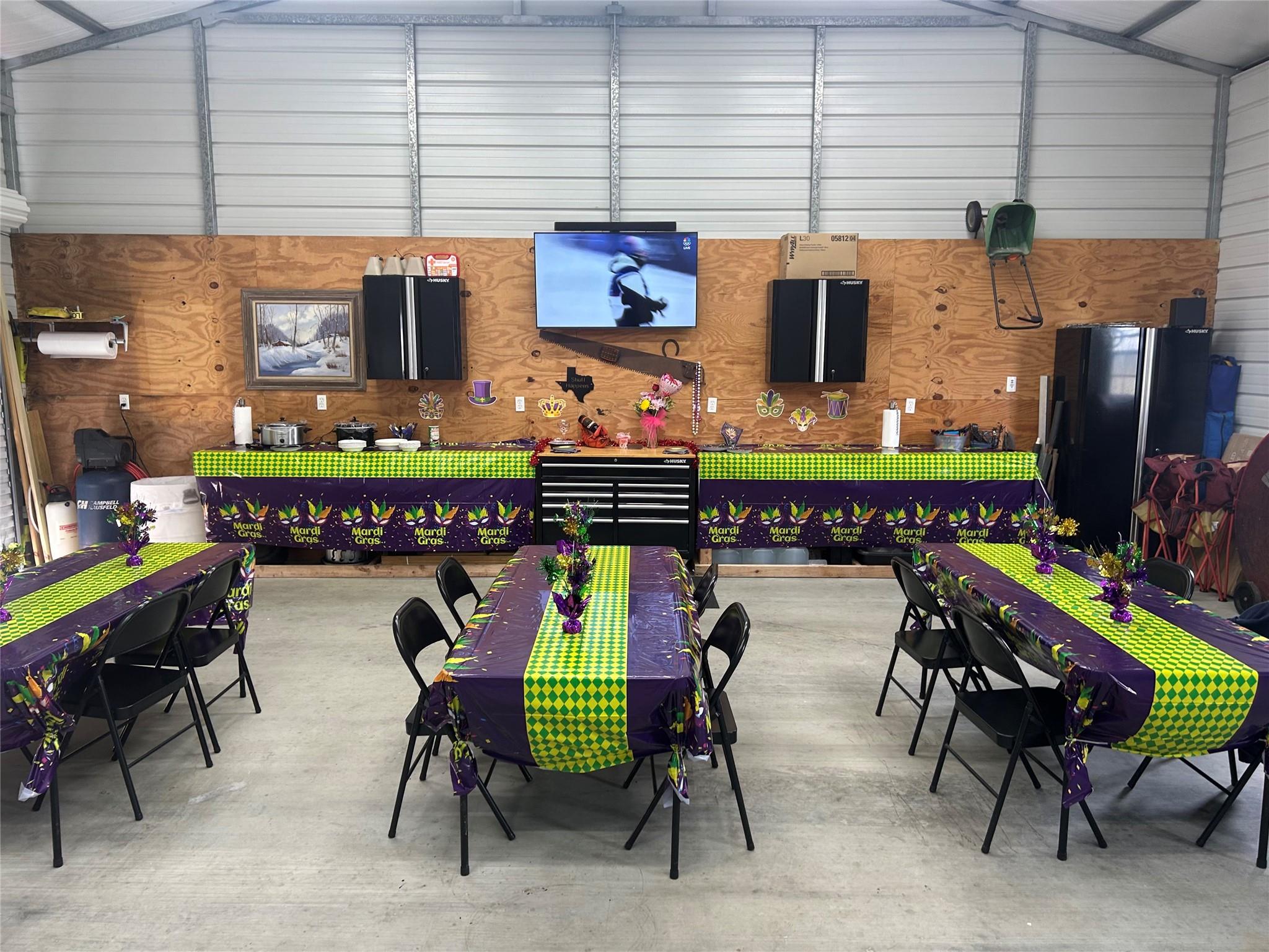 Garage party room with Mardi Gras-decorated tables, folding chairs, and tool cabinets.