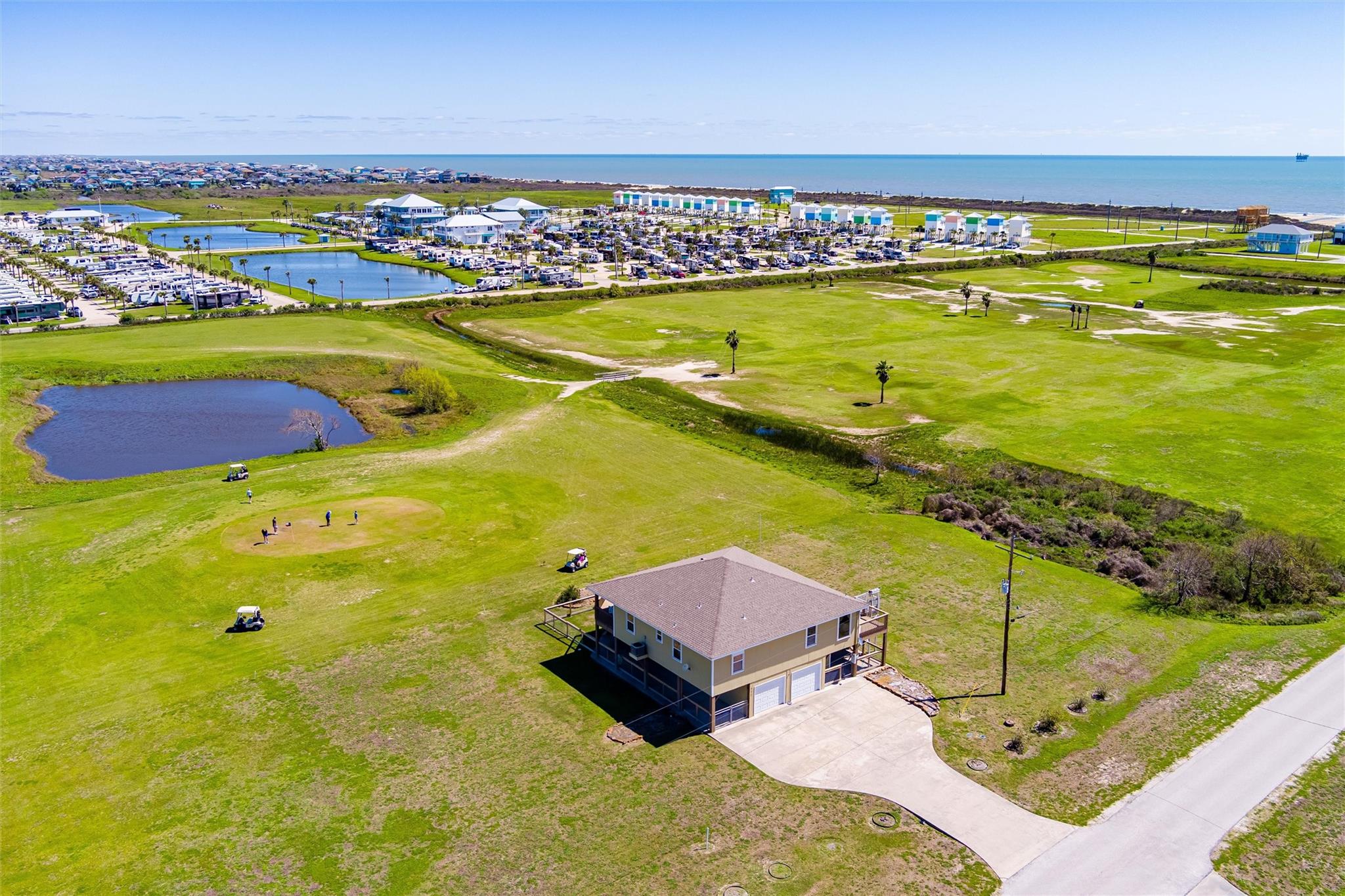 Coastal home beside a golf course, with ponds and the Gulf visible beyond.