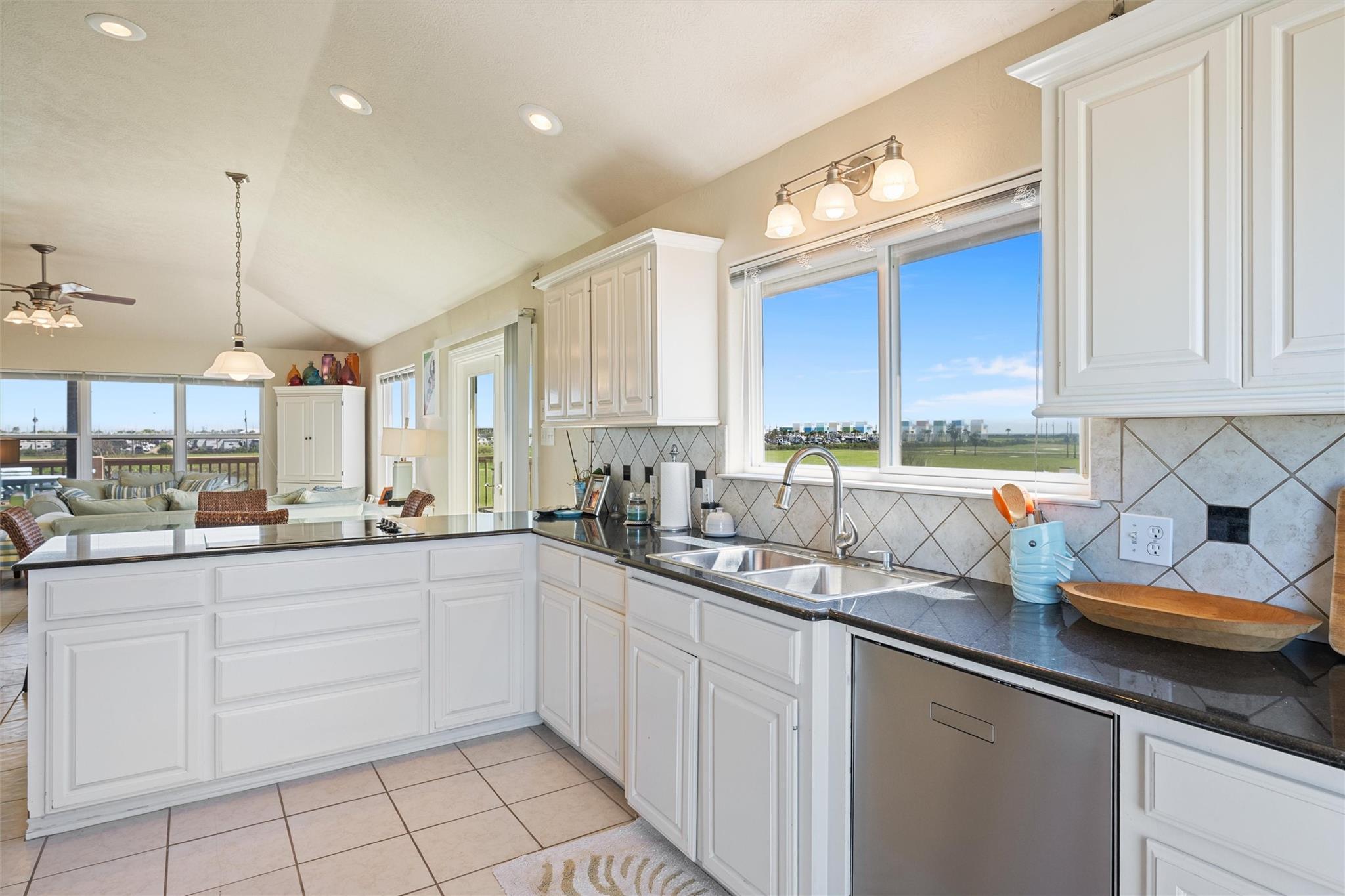Bright white kitchen with a double sink beneath large windows and views of a green lawn.