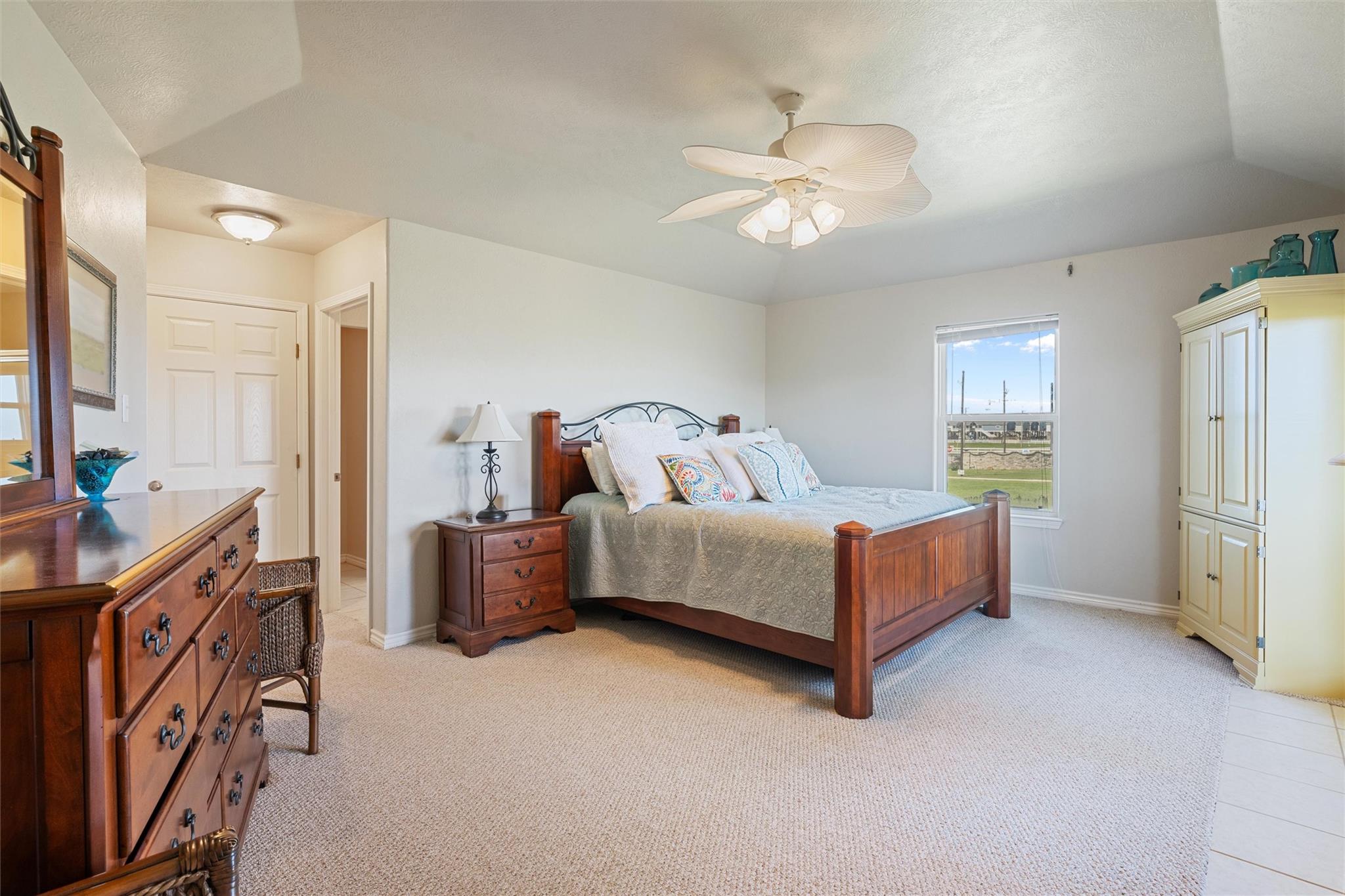 Furnished bedroom with a wooden bed, matching dresser, and ceiling fan.
