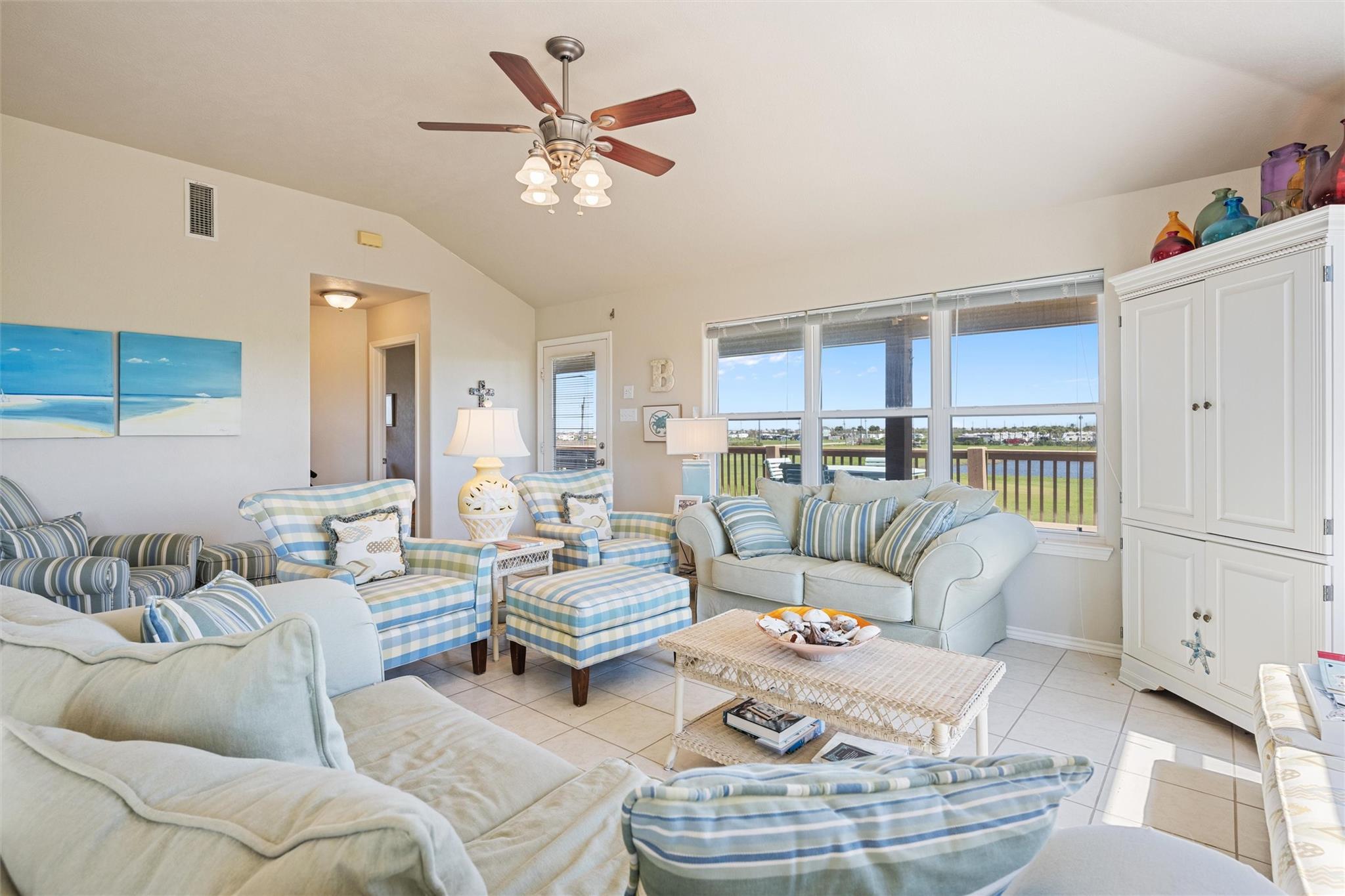 Living room with blue-and-white seating and large windows overlooking a waterway.