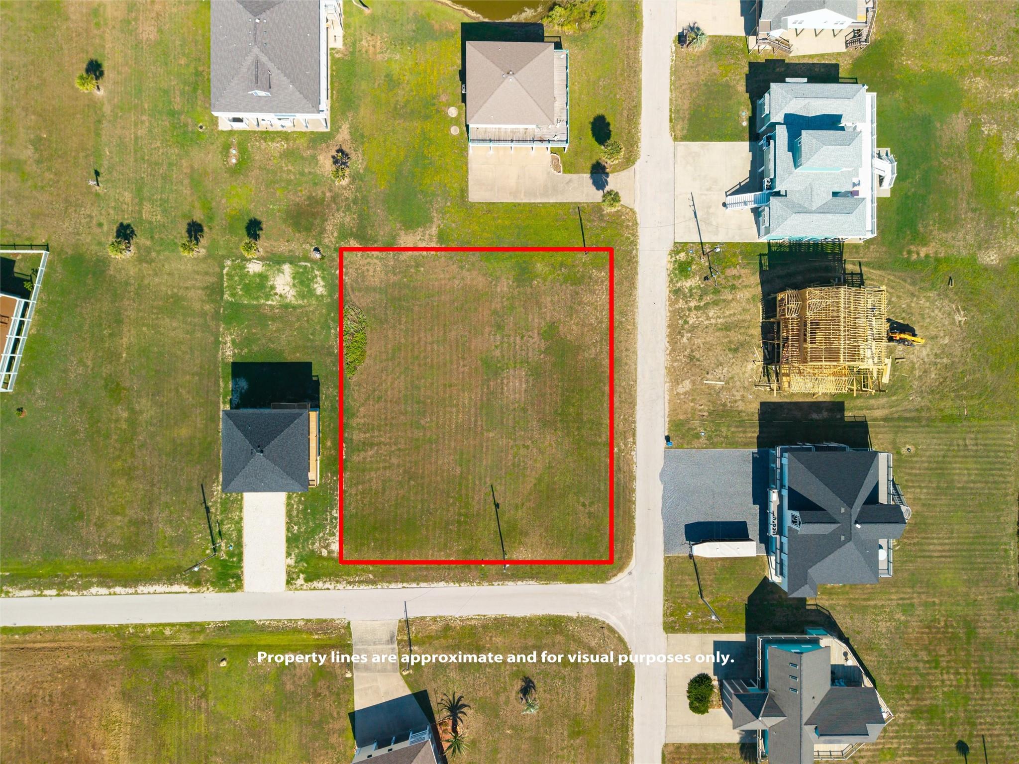 Aerial view of a vacant lot outlined in red beside a residential street.
