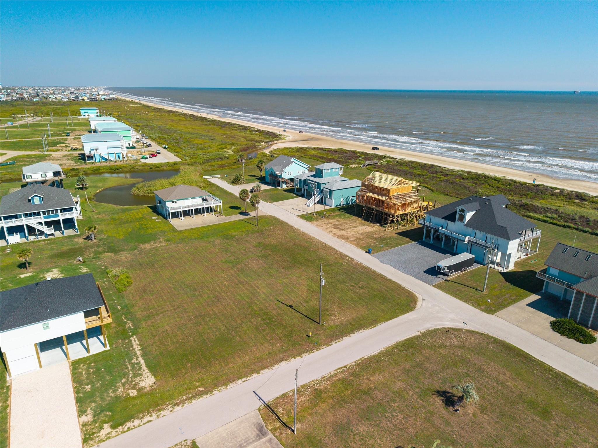 Aerial view of coastal homes along the beach, with a house under construction.