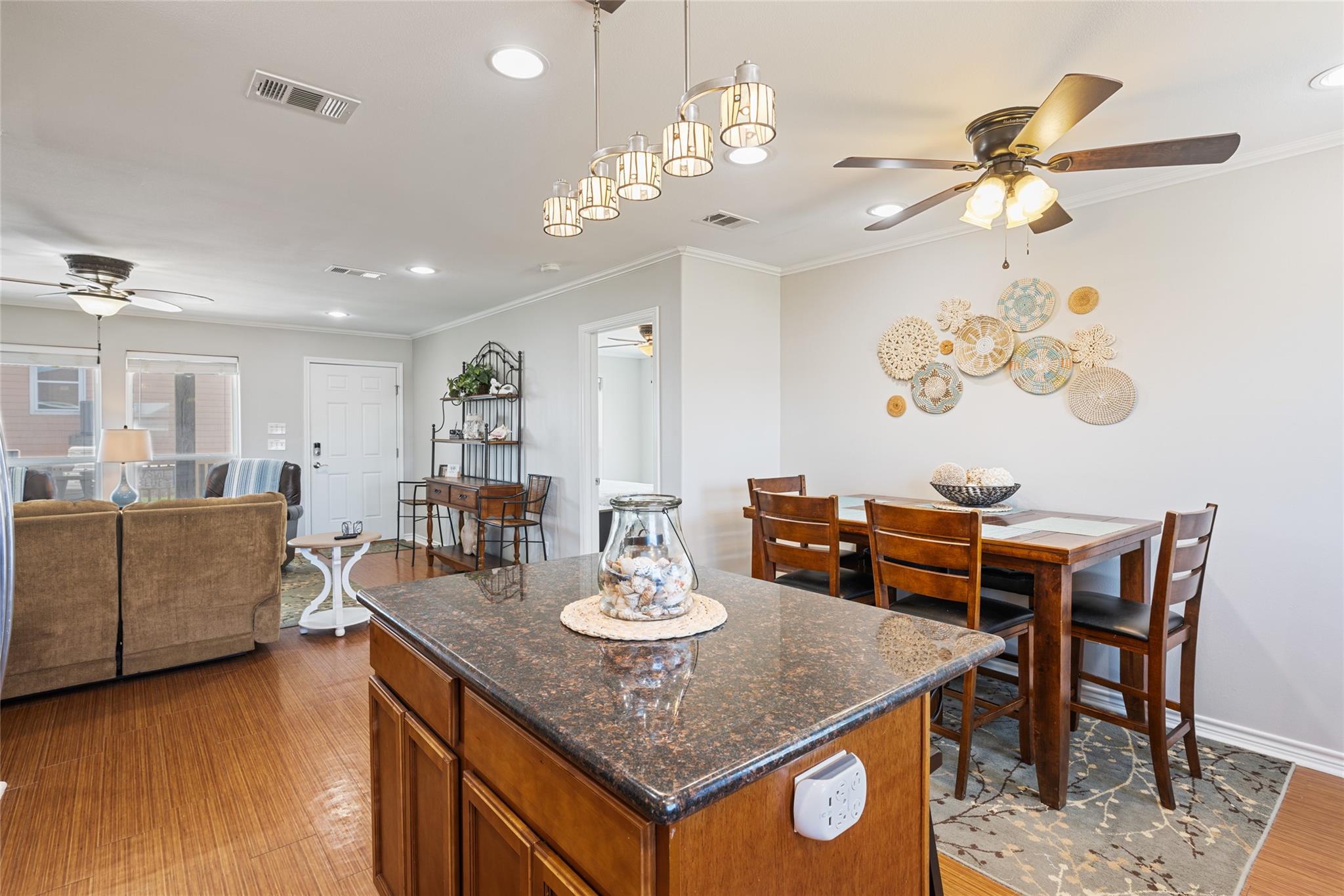 Open-plan kitchen and dining area with a granite island, wooden table, and living room beyond.