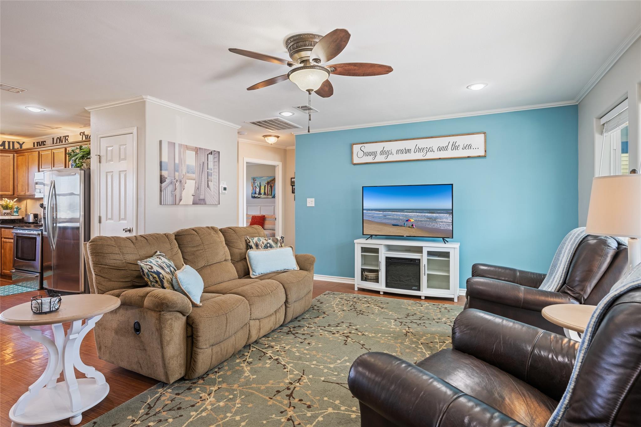 Furnished living room with tan reclining sofa, dark leather chairs, and a blue accent wall.