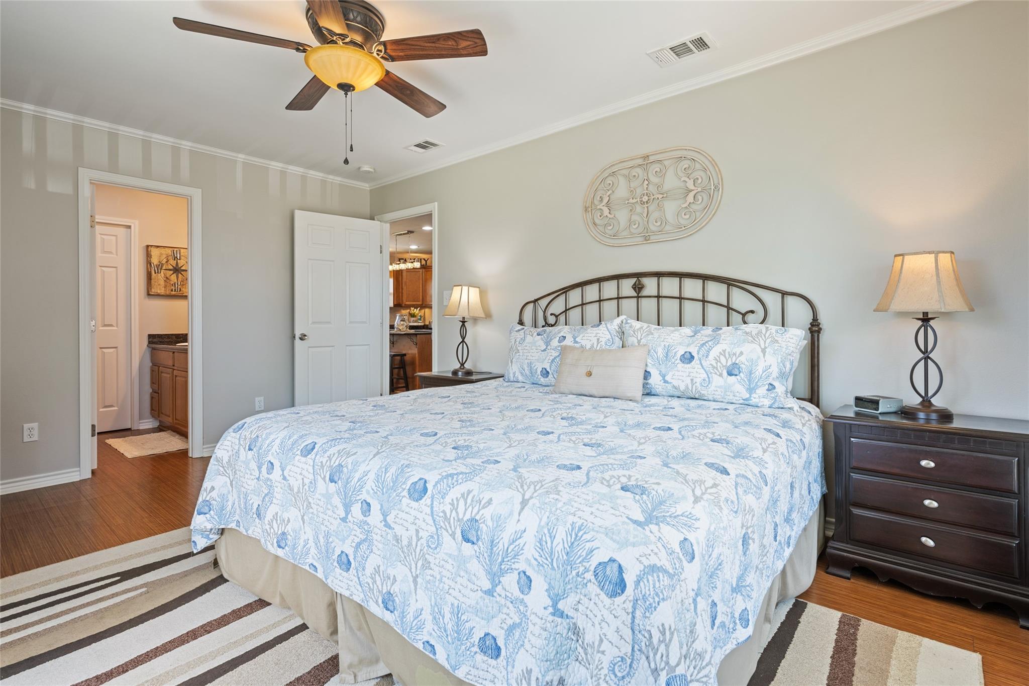 Bedroom with blue-and-white coastal bedding, dark metal headboard, and open doorway to an adjoining bathroom.