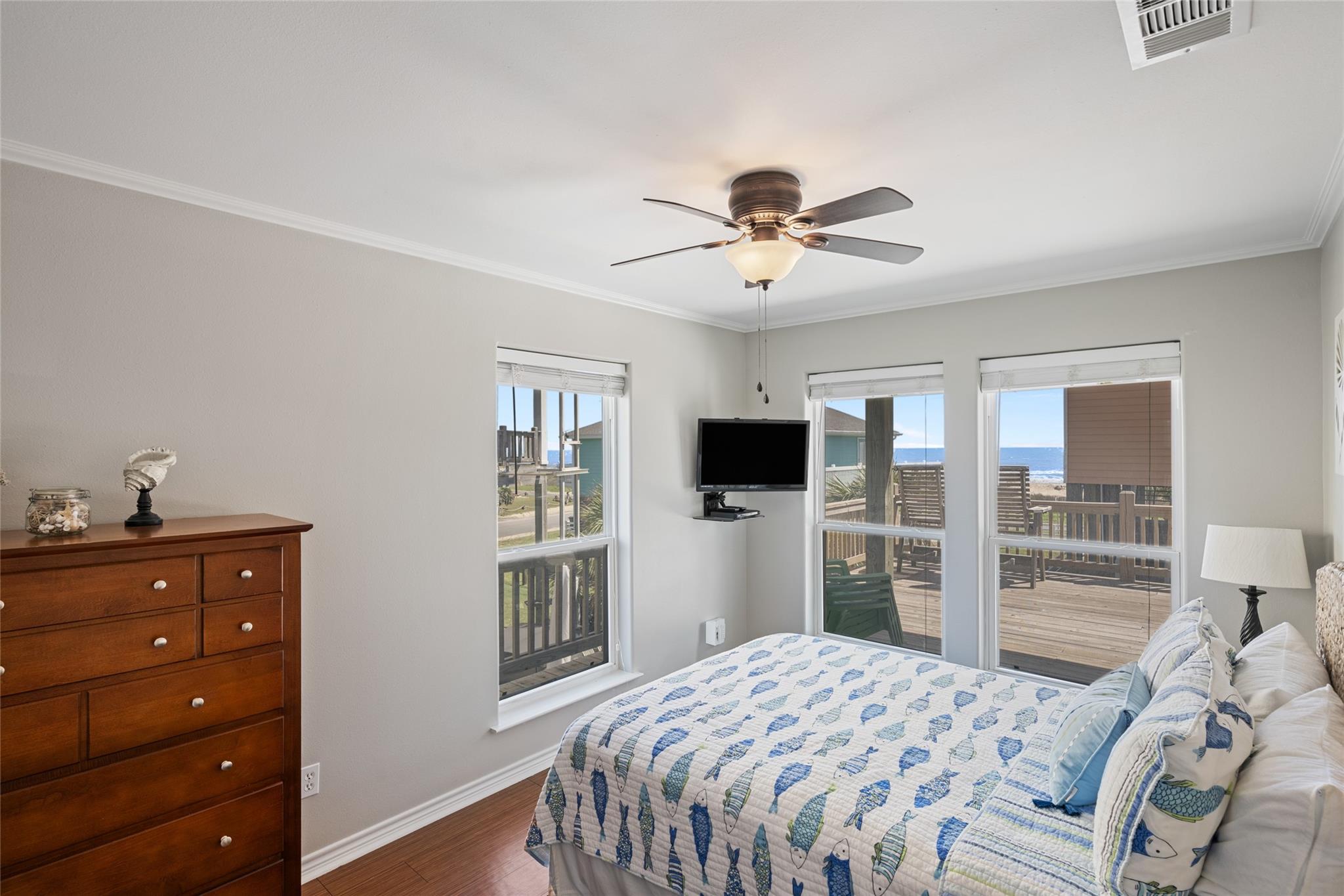 Bedroom with fish-patterned bedding and windows overlooking the ocean and deck