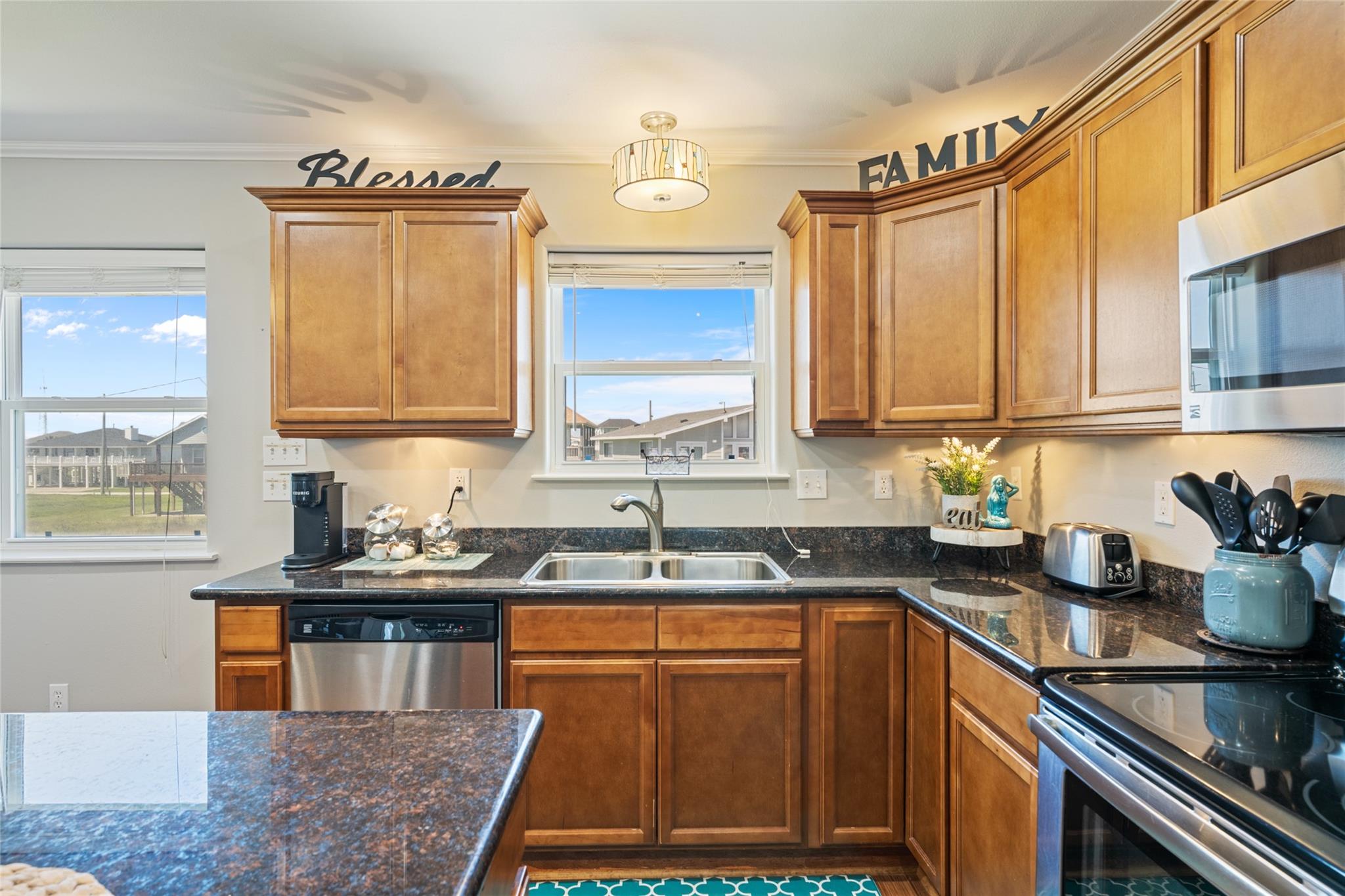 Kitchen with warm wood cabinets, dark granite counters, and stainless steel appliances.