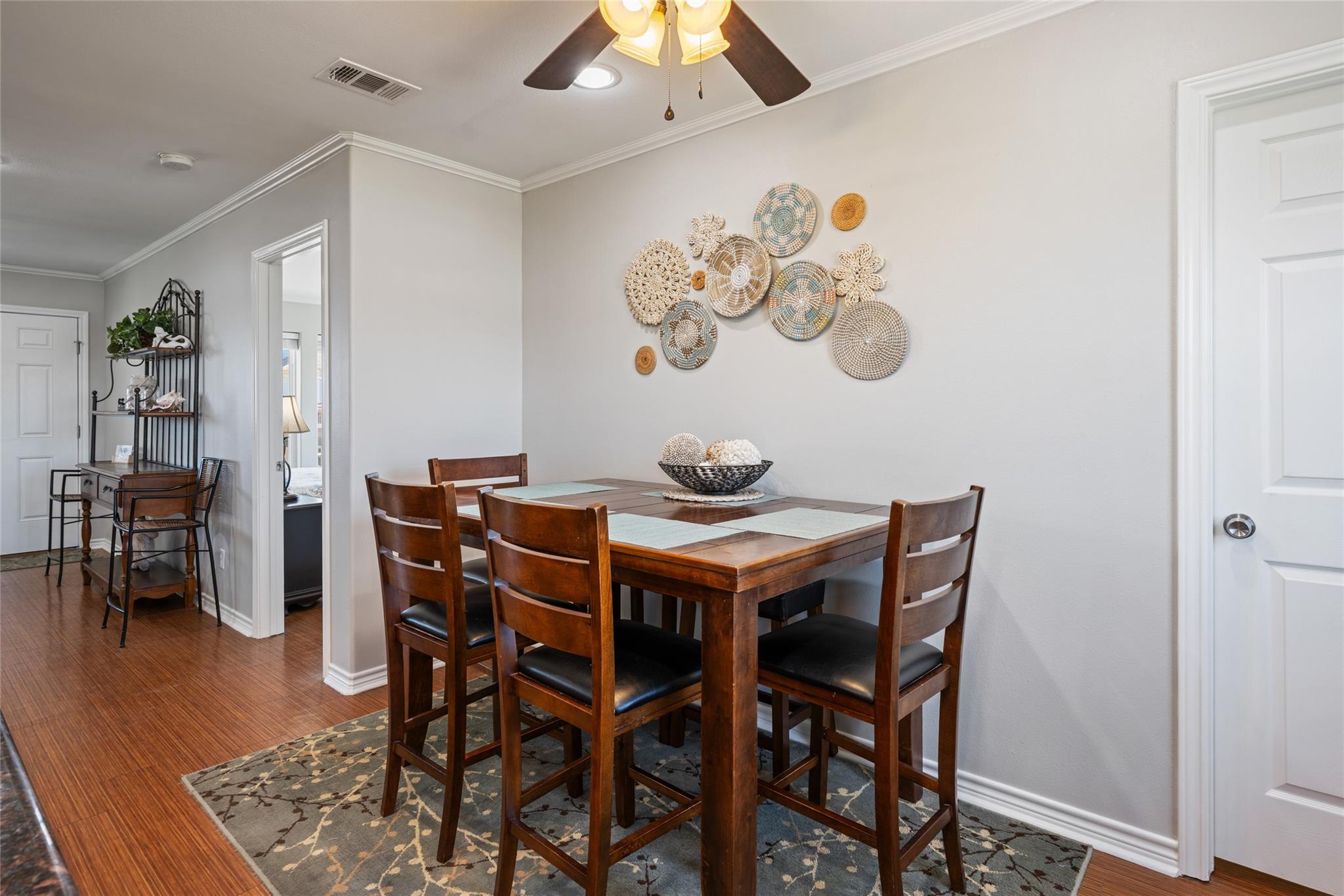 Dining room with a dark wood table, matching chairs, patterned rug, and woven wall decorations.