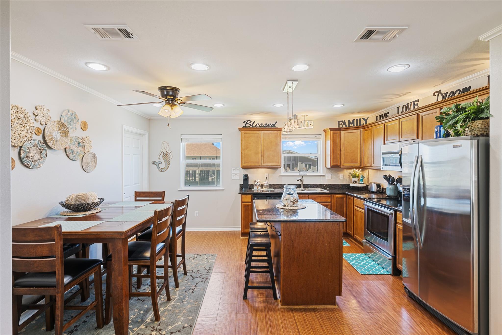 Kitchen and dining area with warm wood cabinets, a central island, stainless appliances, and a large dining table.