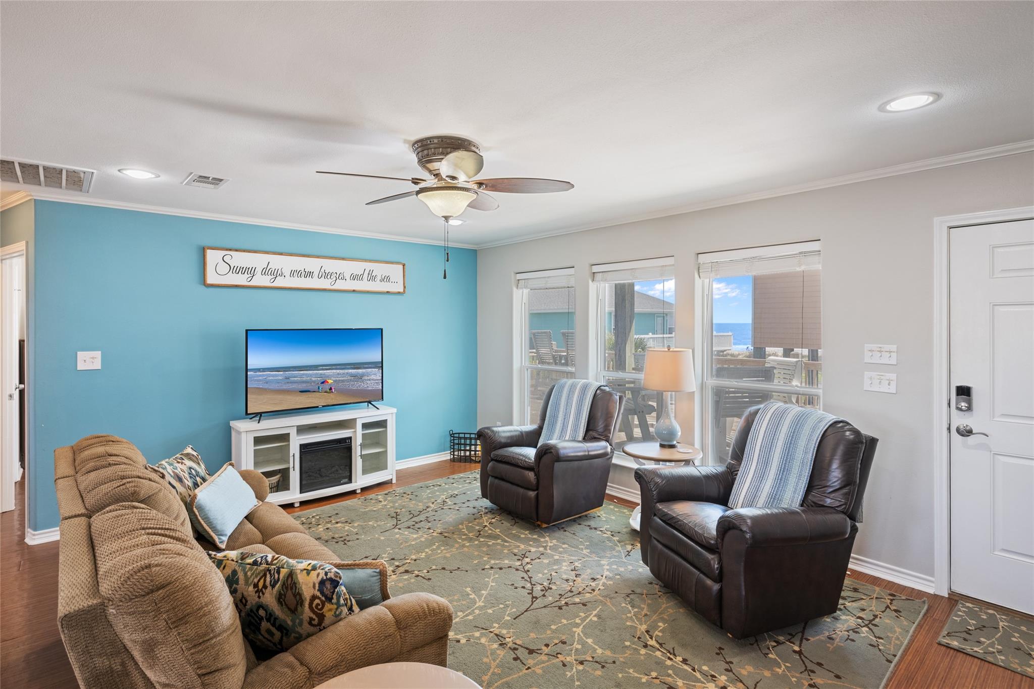 Living room with turquoise accent wall, leather recliners, and ocean views through the windows.