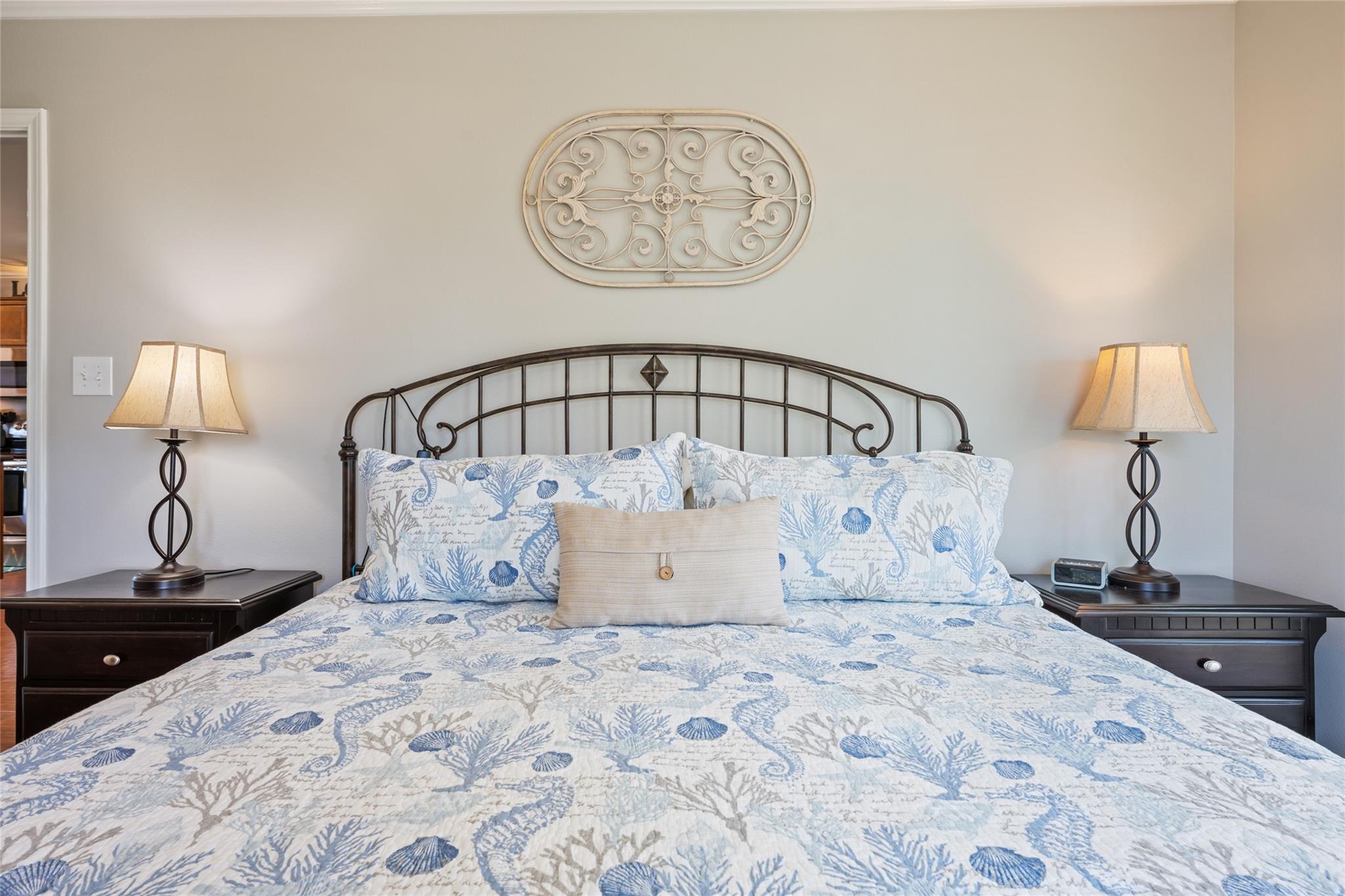 Bedroom with blue-and-white coastal-patterned bedding, an arched metal headboard, and matching bedside lamps.