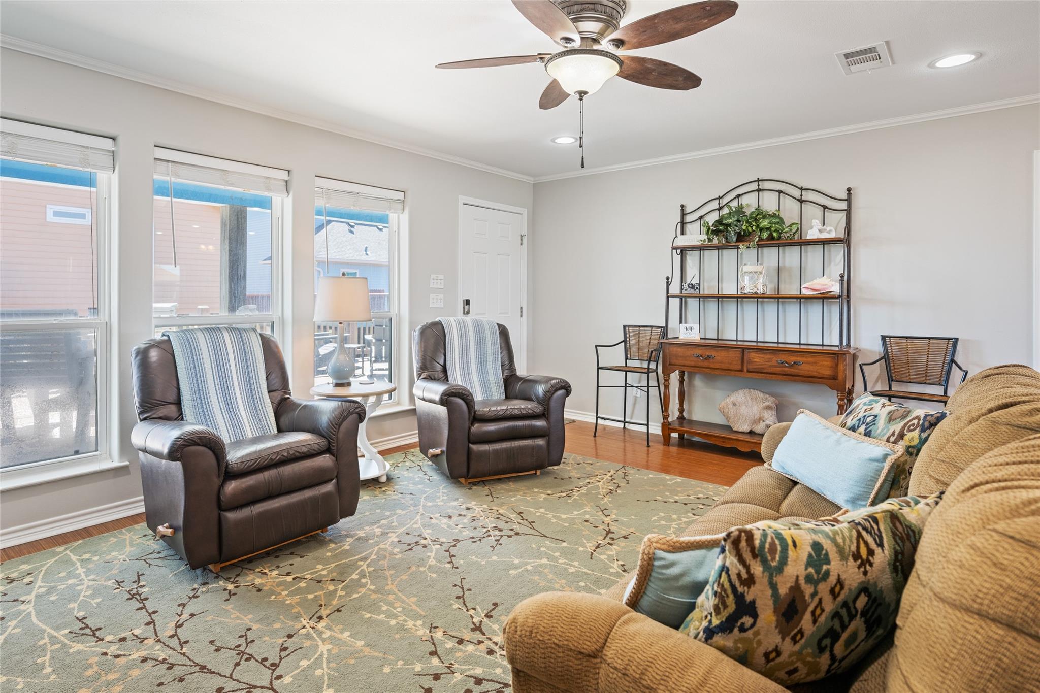 Furnished living room with leather recliners, a tan sofa, and large windows.