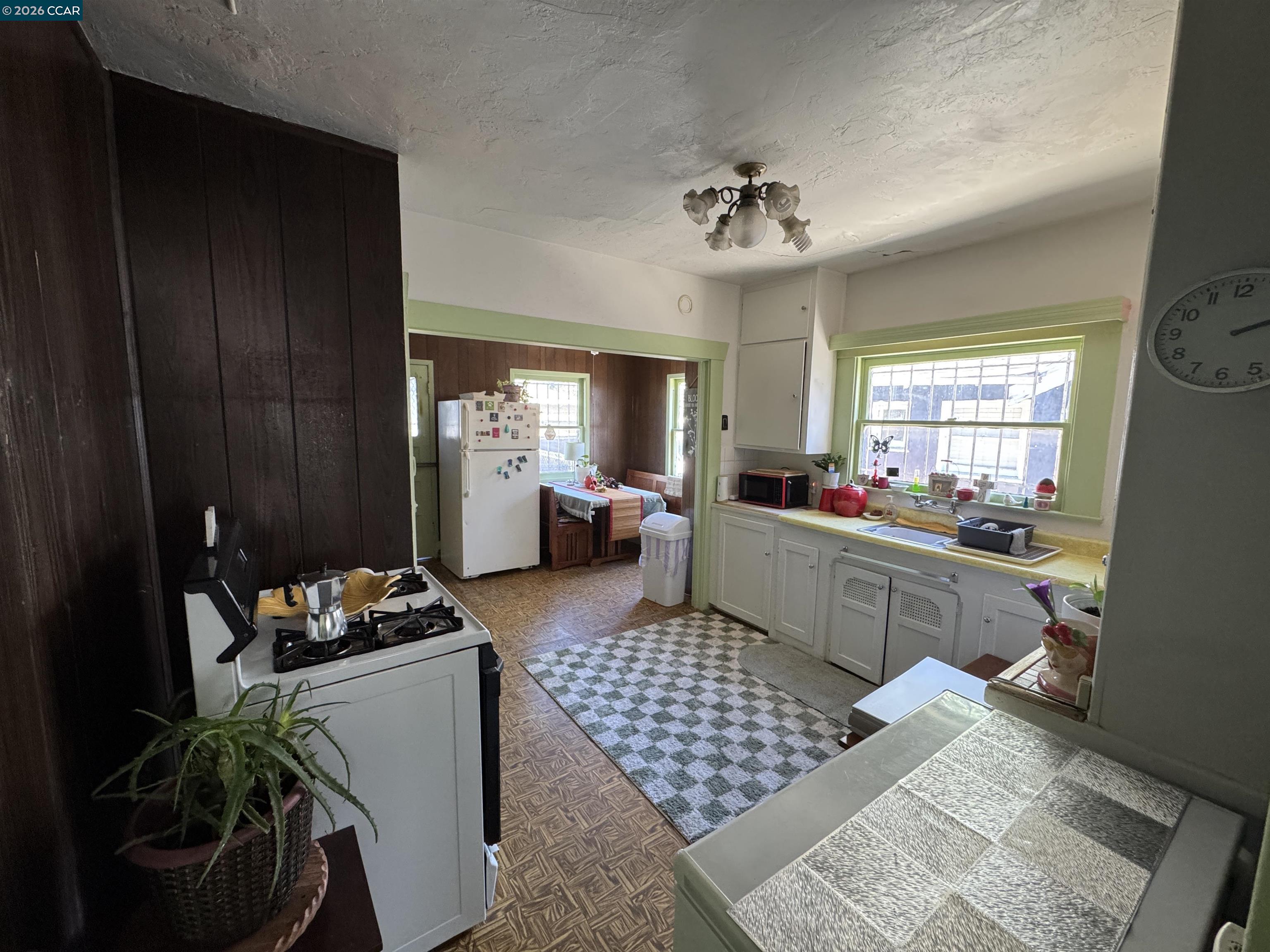 Kitchen with green-trimmed windows, a gas stove, white cabinets, and an adjoining dining nook.