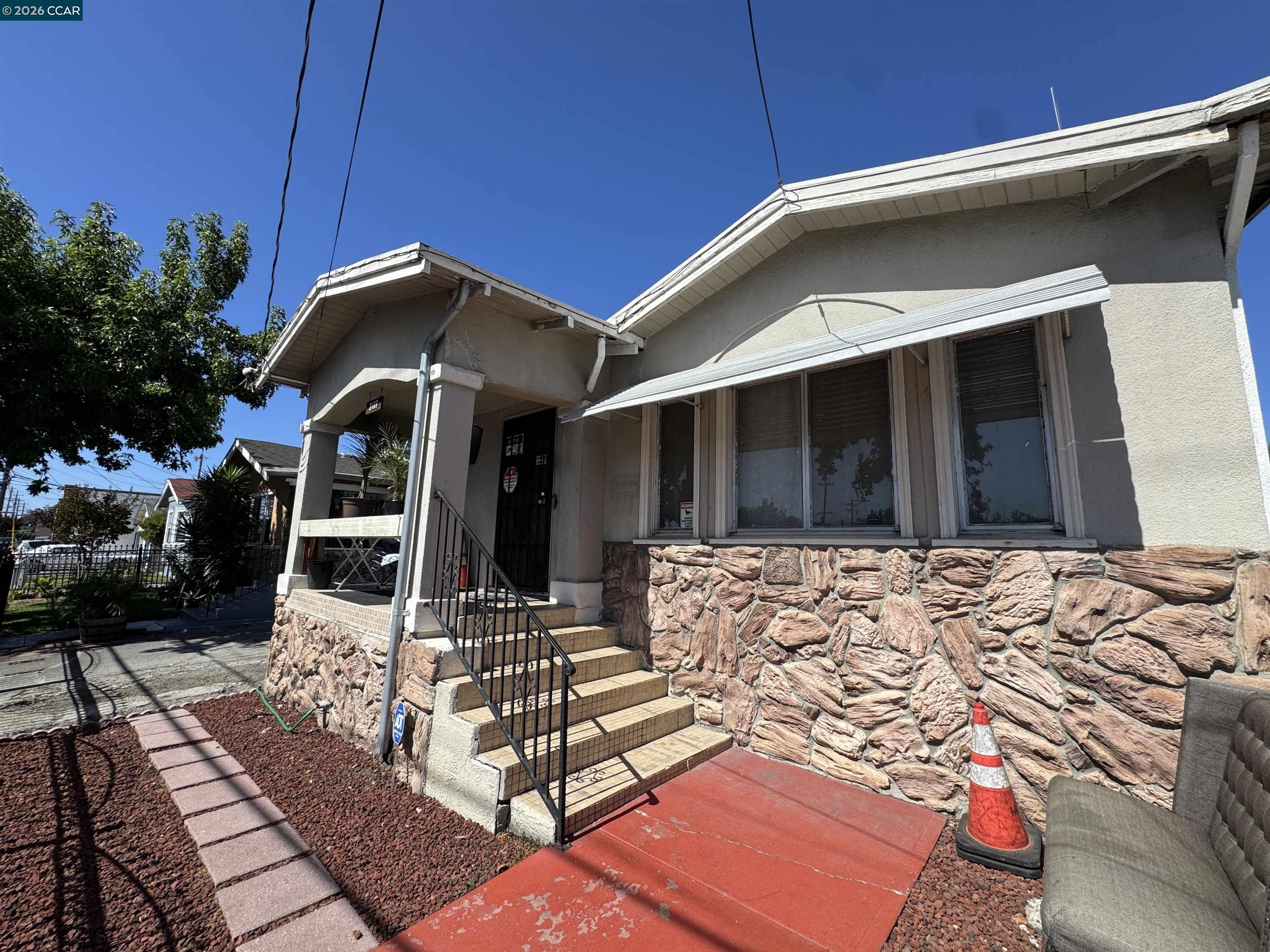 Building exterior with stone veneer, covered entrance, tiled steps, and red-painted walkway.