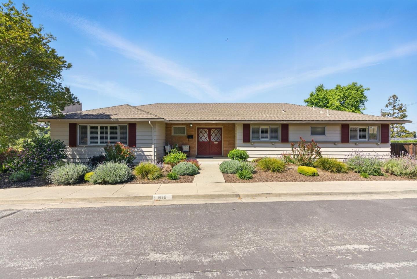 Single-story ranch house with red entry doors and a landscaped front yard.