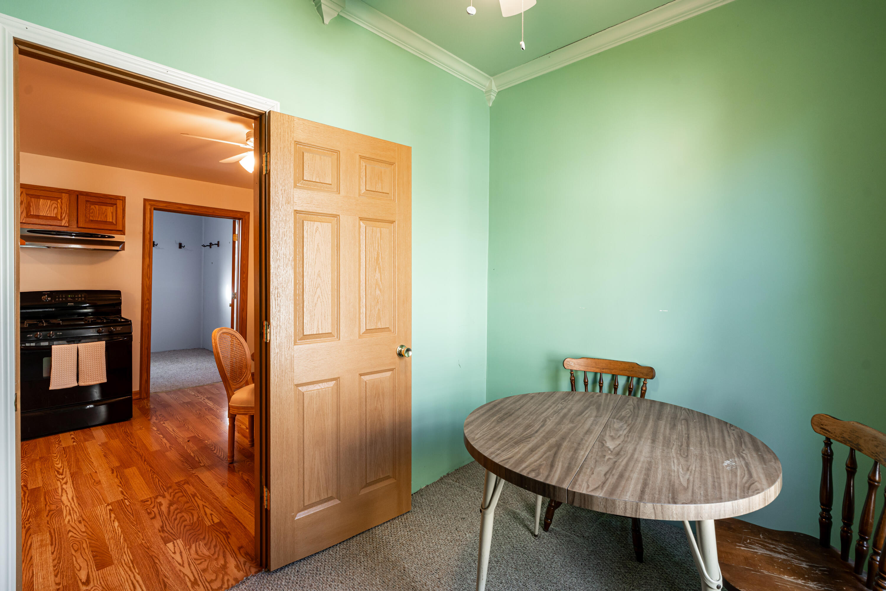 Dining area with mint-green walls, an oval table, and an open doorway to the kitchen.