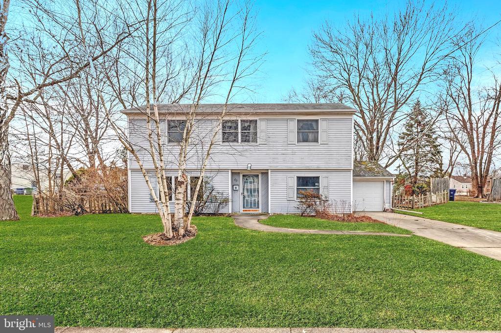 Two-story gray-sided home with an attached garage, curved walkway, and broad green lawn.