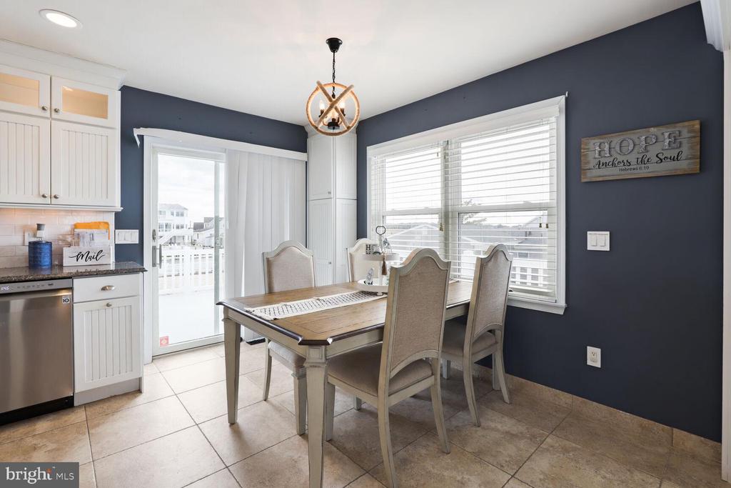 Dining area with a wood table and upholstered chairs beside a white kitchen.