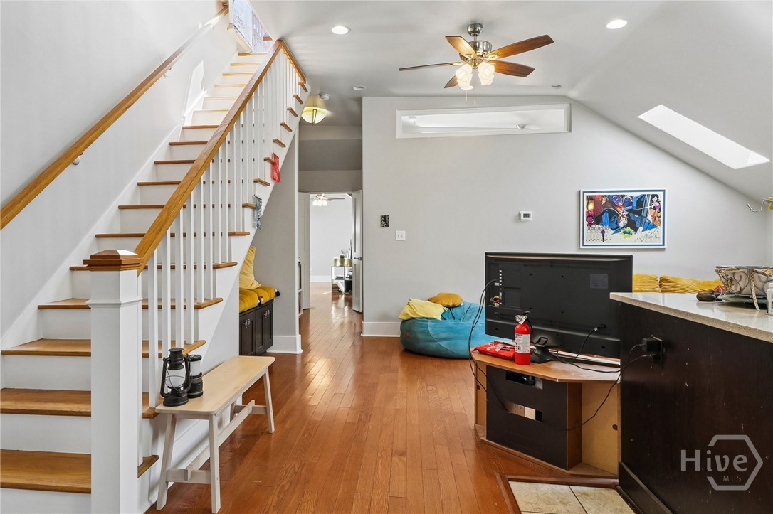 Upstairs living area with hardwood floors, a wood-and-white staircase, and sloped ceilings.
