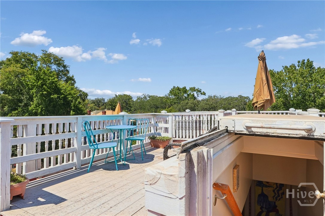 Rooftop deck with turquoise patio furniture, white railings, and an open stairwell.