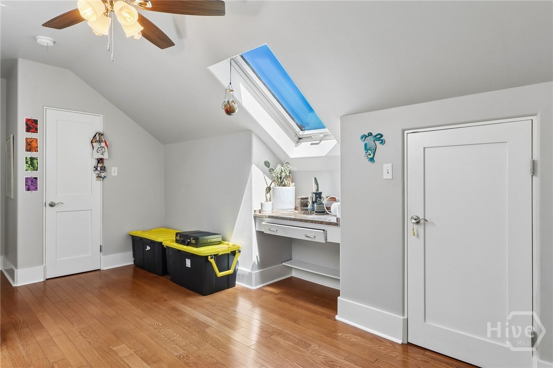 Bright room with a skylight, hardwood floors, built-in counter, and storage bins.