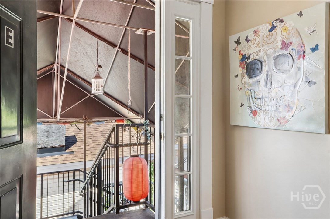 Open doorway to a covered balcony with black railings and a red lantern; floral skull artwork hangs inside.