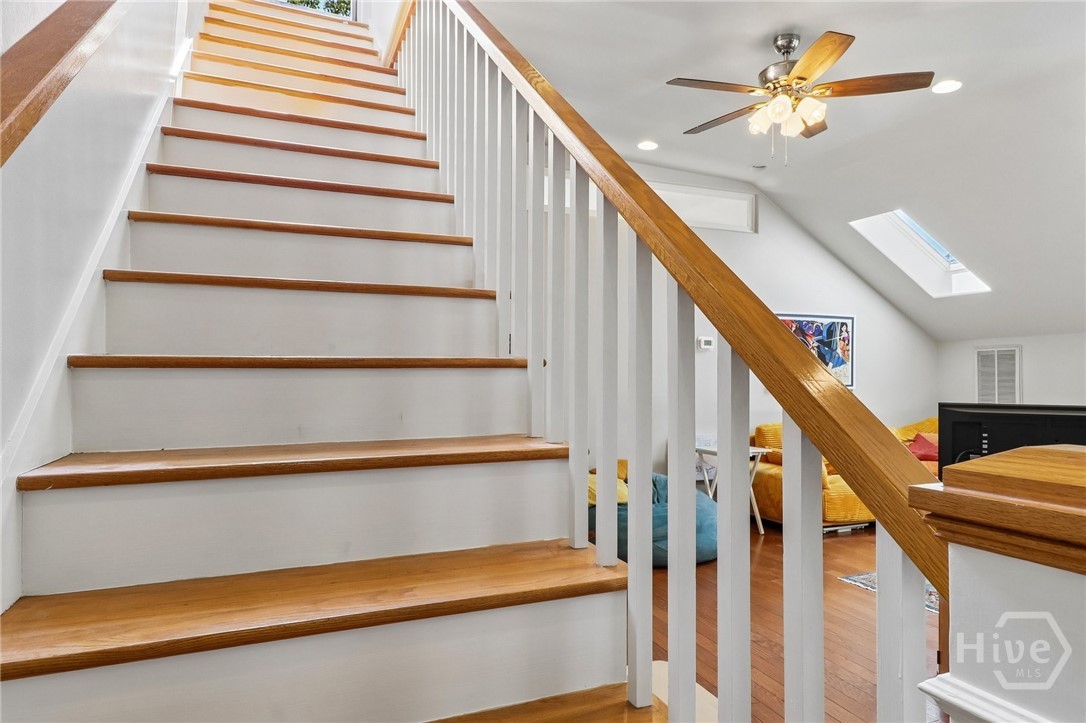 White staircase with wooden treads and railing overlooking a furnished upper-level living area.