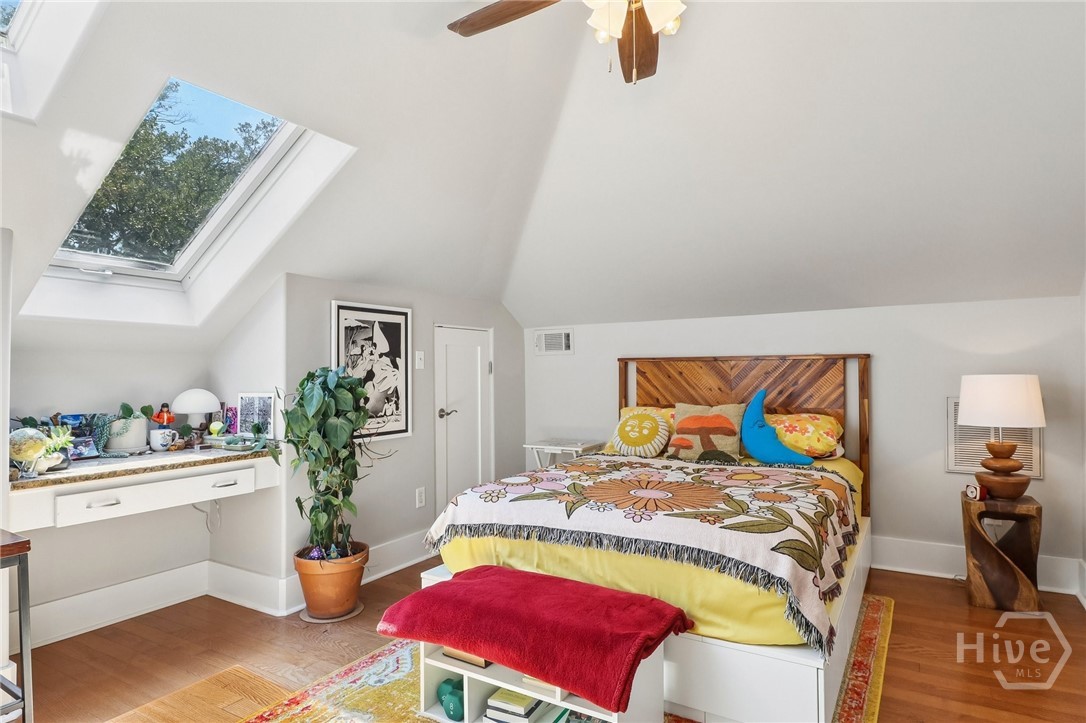 Attic bedroom with a large skylight, wooden headboard, and colorful floral bedding.