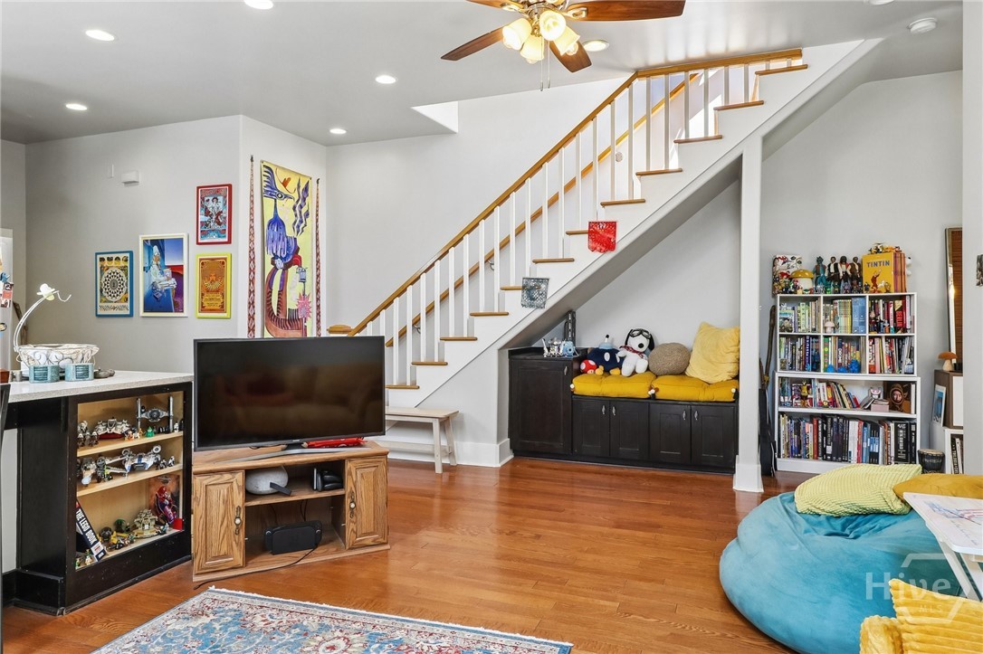 Living room with a wood staircase, hardwood floors, and a cushioned built-in bench beneath the stairs.